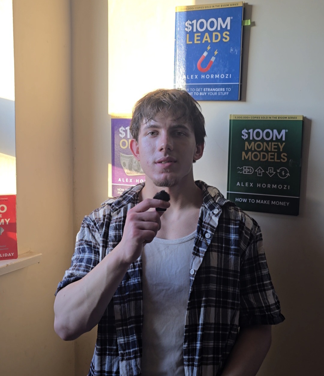 Qendrim Hasani, host of The Front Desk, holding a mic in front of a wall of business books